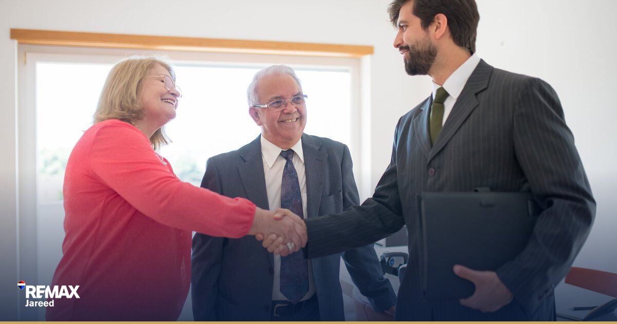 Property consultant shaking hands with client after closing first real estate transaction in modern office