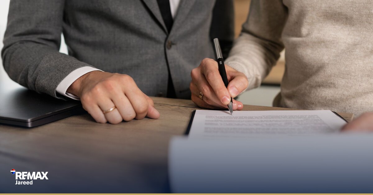 شخص يقرأ جدول سداد عقاري مع آلة حاسبة ومستندات على طاولة